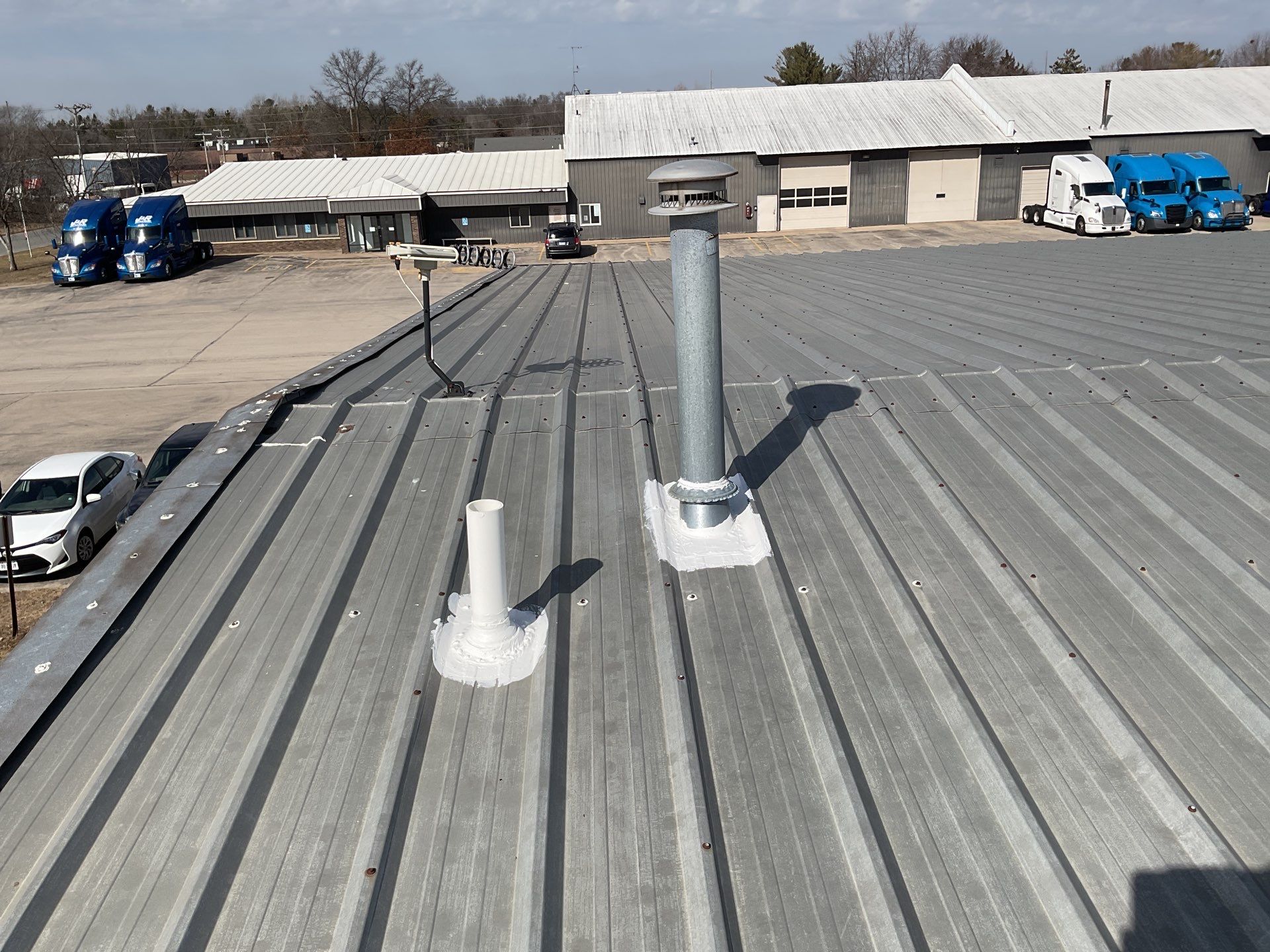Metal roof with pipe penetrations at commercial trucking facility