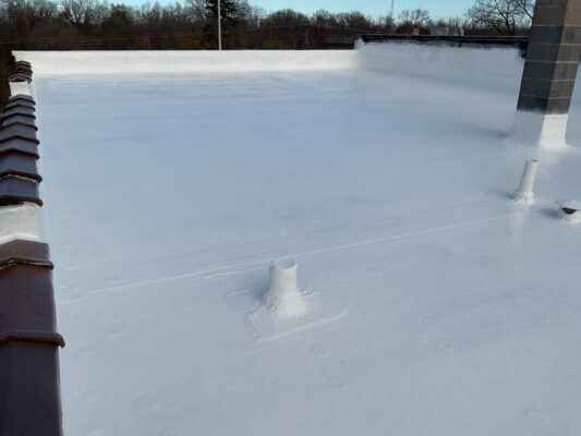 Freshly coated white flat commercial roof with pipe penetrations