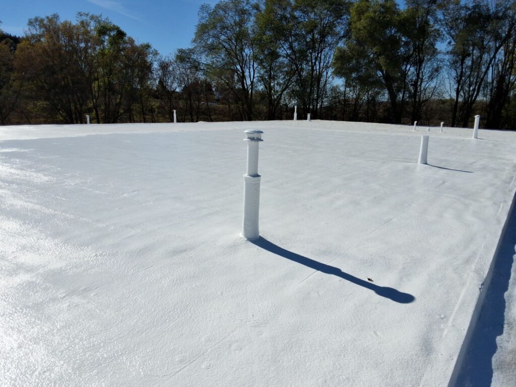 White coated flat commercial roof with ventilation pipes and SPF Roof Coating