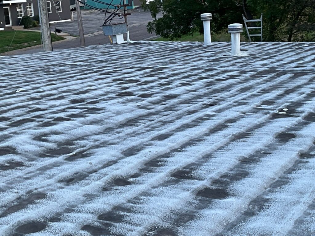 Frost-covered flat roof with vent pipes and ladder